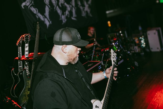 A guitarist playing beside the drum kit