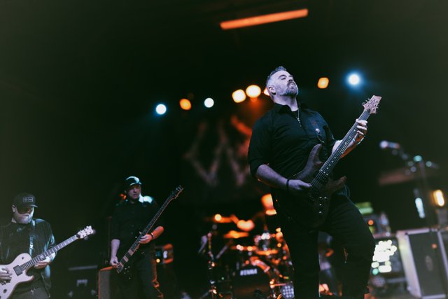 A guitarist performing under green stage lights