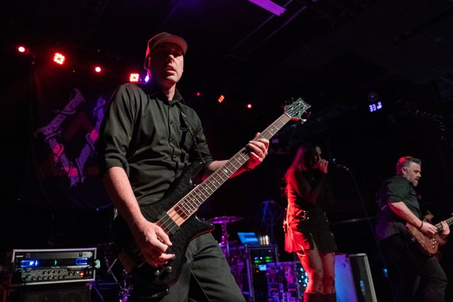 A guitarist playing under red and purple lights
