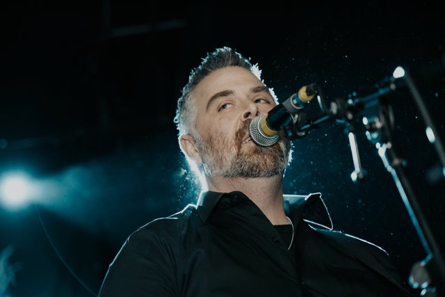 A guitarist singing into his microphone