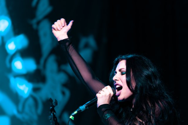 Sarah singing with one arm raised