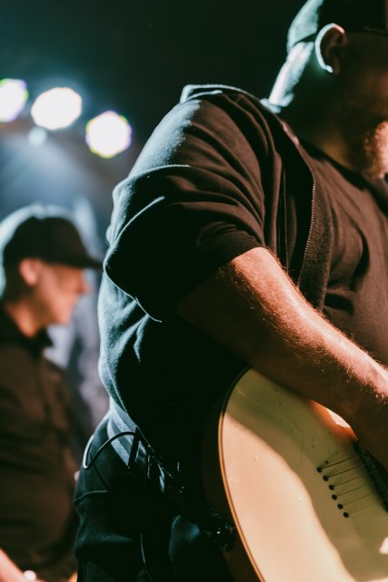 A close view of a guitarist under white stage lights
