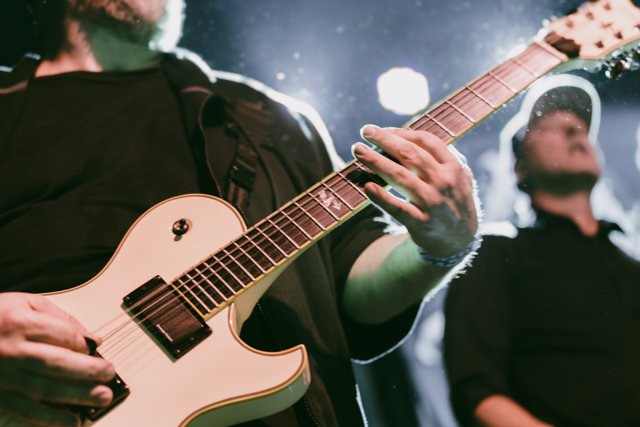 A close view of hands playing a white guitar