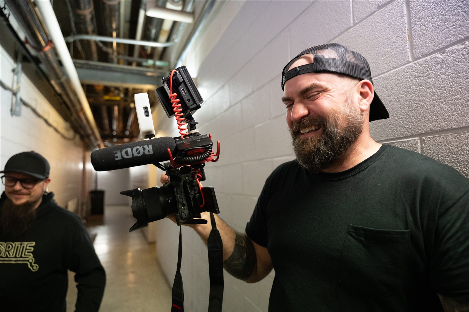 A photographer holding a camera in the backstage corridor