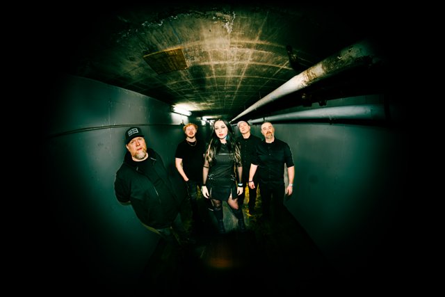 The band standing together beneath corridor lights