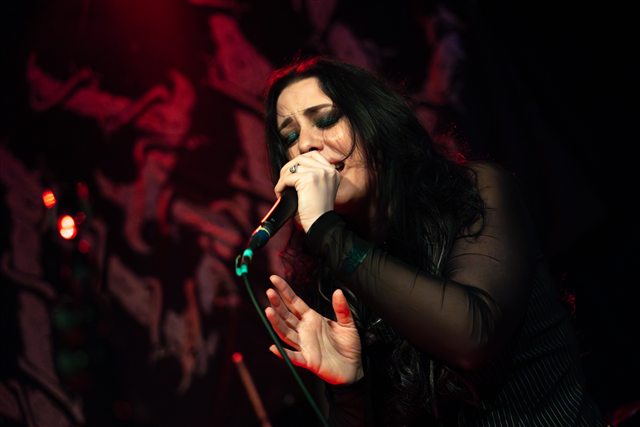 Sarah singing in red stage lighting