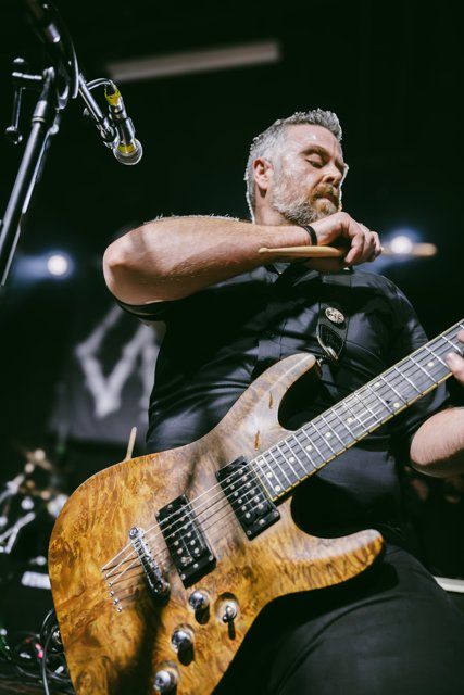 A guitarist reaching forward during the performance