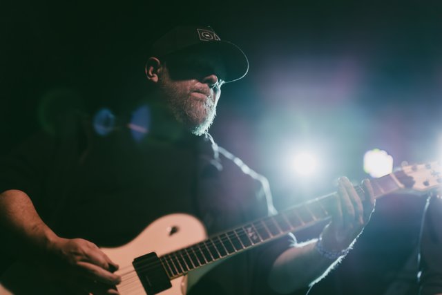 A guitarist playing beneath a bright stage light