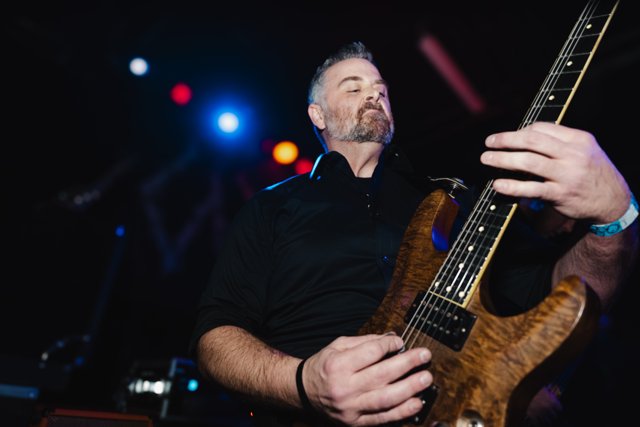 A guitarist playing beneath blue and red lights