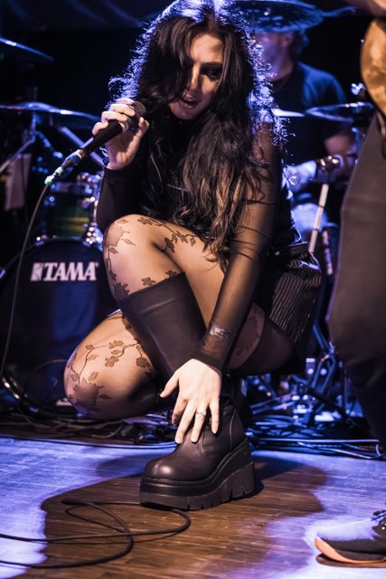 Sarah crouching at the edge of the stage