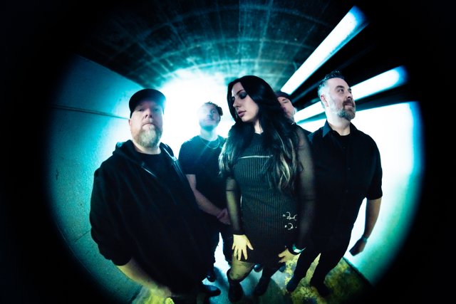The band posing together beneath blue corridor lights