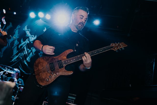 A guitarist playing beneath bright blue lights