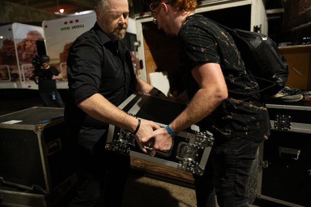 Band members moving equipment backstage