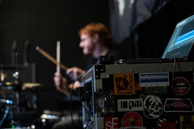 The drummer performing behind backstage equipment