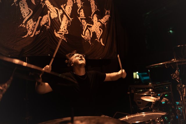 The drummer reaching upward during the set