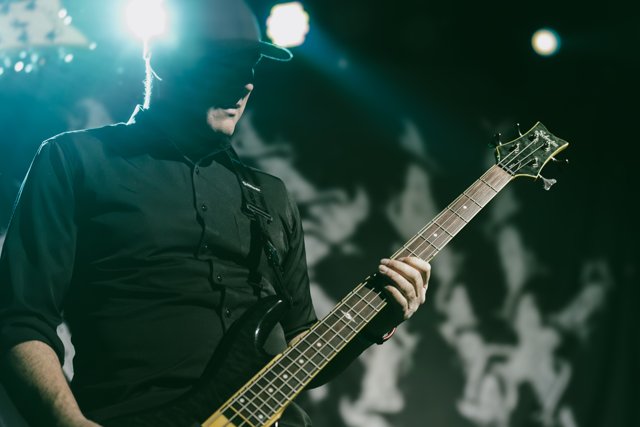 A guitarist playing beneath green stage lights