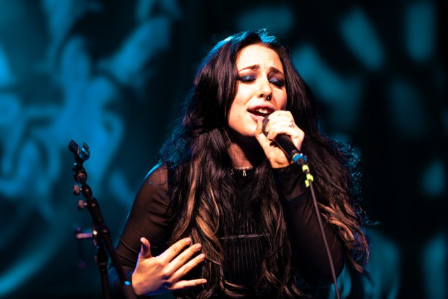 Sarah singing under blue stage lights