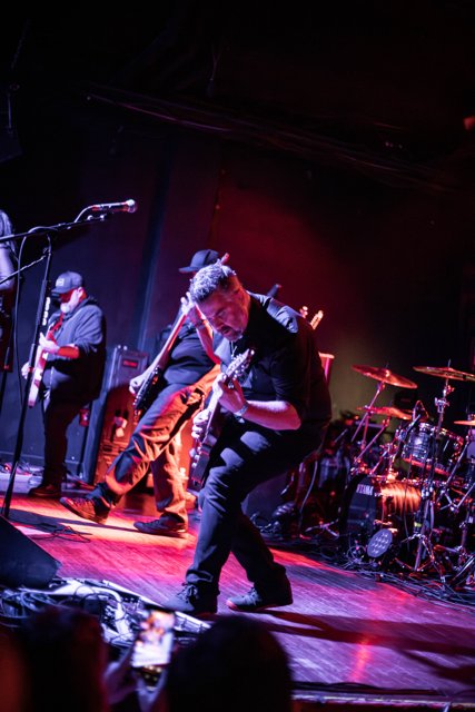 A guitarist performing beneath red and blue lights