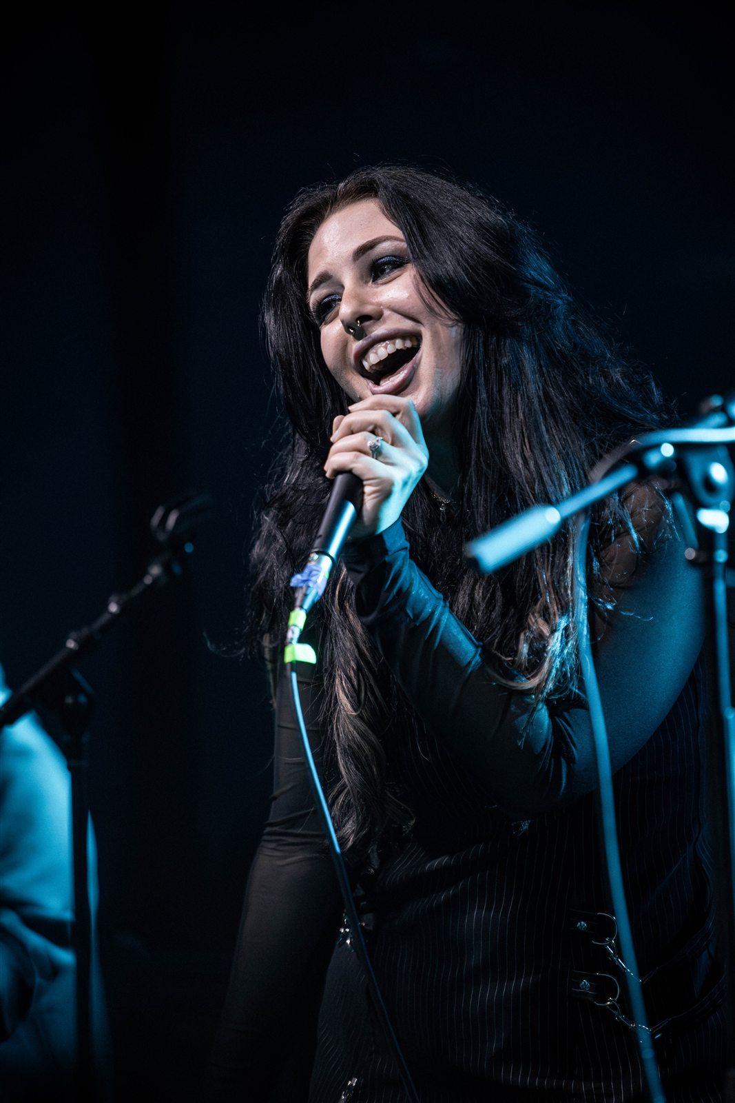 Sarah smiling with the microphone in blue stage light