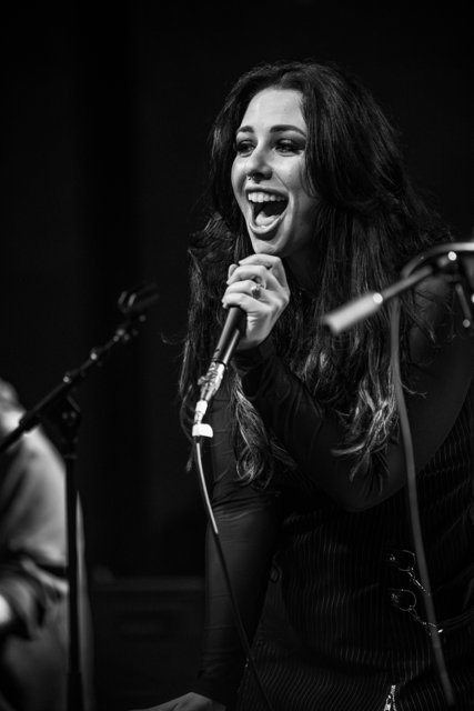 Sarah smiling with the microphone in black and white