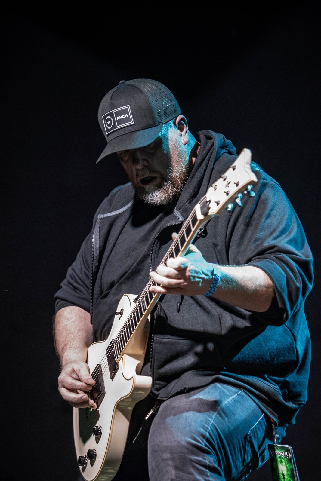 A guitarist concentrating on his instrument under blue lighting
