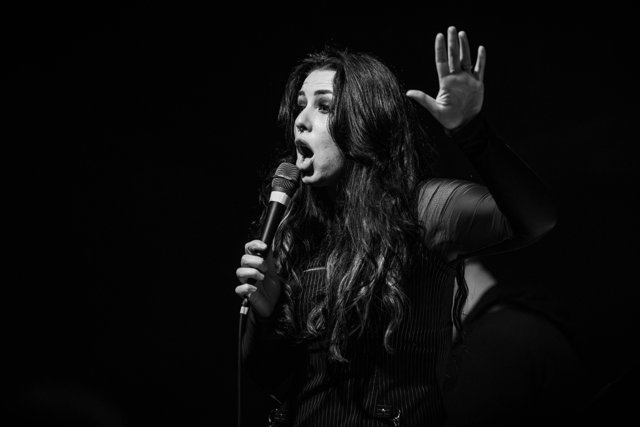 Sarah waving toward the crowd in black and white
