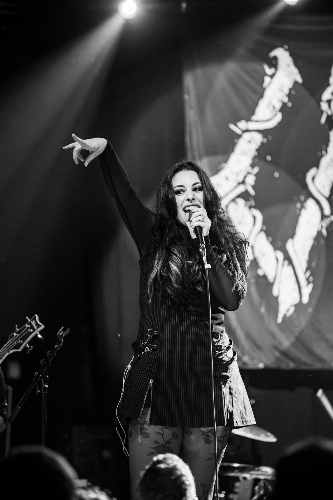 Sarah raising one arm toward the room in black and white
