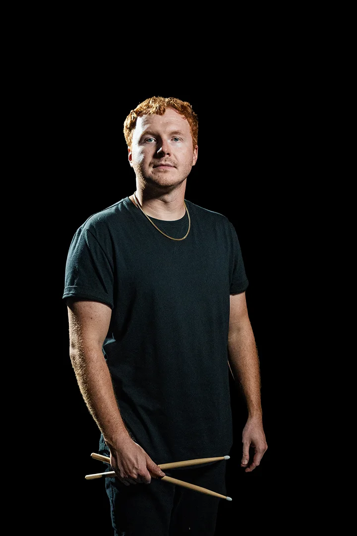 James Rollins holding drumsticks against a black background